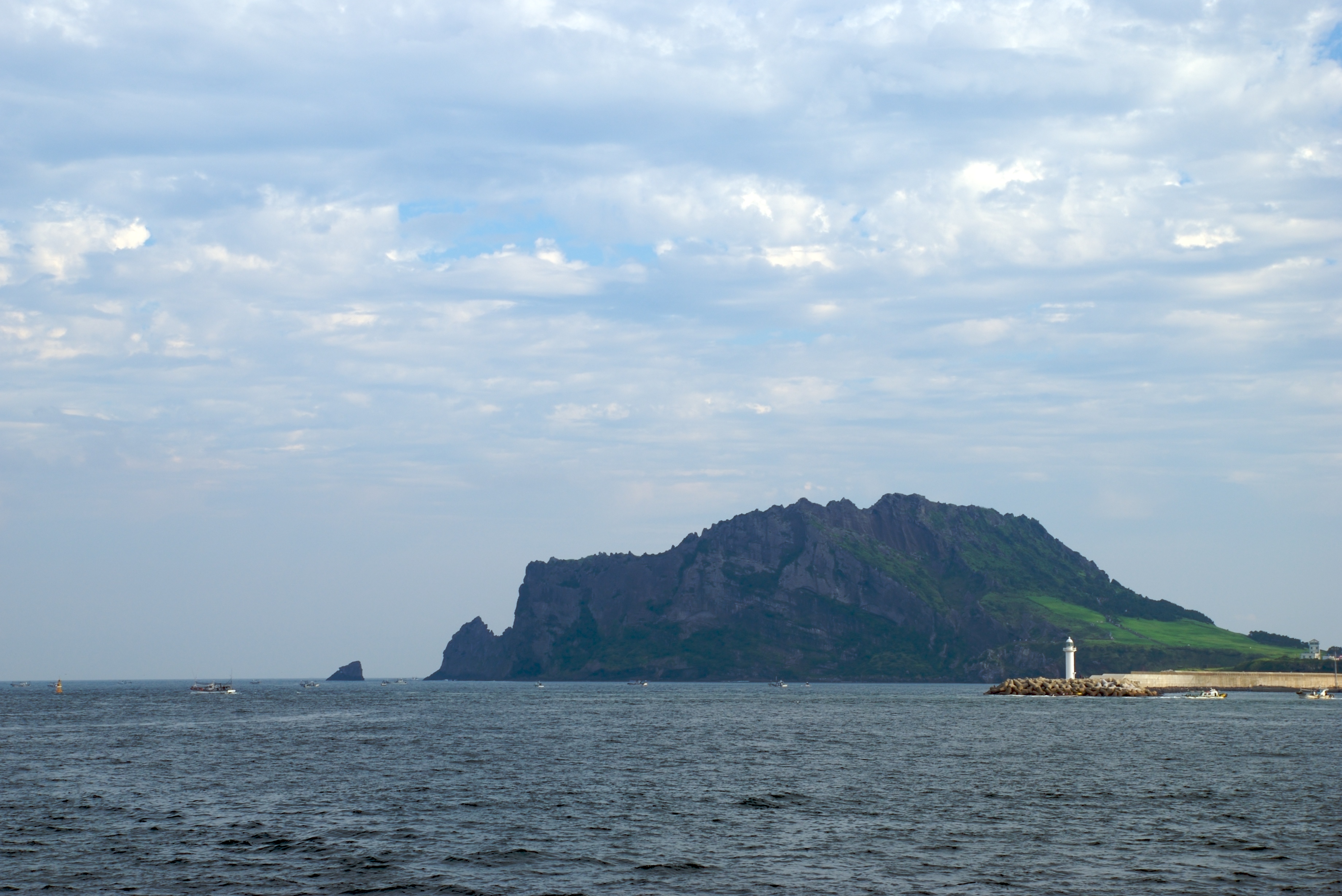 从海上远望济州岛城山日出峰,蓝色海面与火山相接